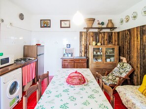 Une cuisine compacte comprenant un coin repas, un lave-linge, un four à micro-ondes et un meuble avec des portes en verre.