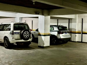 Eine Tiefgarage mit zwei weißen SUVs, geparkt unter Betonstützen.