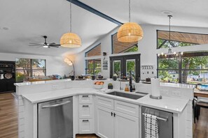 A modern kitchen with white cabinetry, a large island, and pendant lighting. - Lakeshore Retreat | Pool, Spa & Private Peninsula (Kingsland)