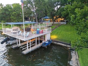 A waterfront property with a floating deck, a covered seating area, and a boat docked nearby. - Lakeshore Retreat | Pool, Spa & Private Peninsula (Kingsland)