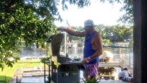 A person grilling outdoors with a view of a water body and a grassy area. - Lakeshore Retreat | Pool, Spa & Private Peninsula (Kingsland)