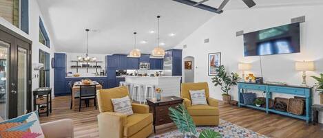 A spacious living area with a high ceiling, a dining area, and a kitchen.