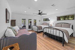 Une chambre avec deux lits, un canapé à motifs à carreaux et un ventilateur de plafond.
