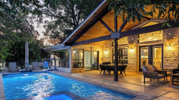 A swimming pool with a patio area, stone walls, and outdoor seating. - Lakeshore Retreat | Pool, Spa & Private Peninsula (Kingsland)