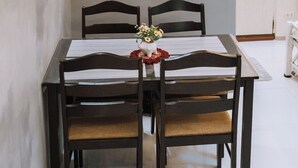 Una mesa de comedor con cuatro sillas, una planta pequeña en maceta y un radio en un estante superior.