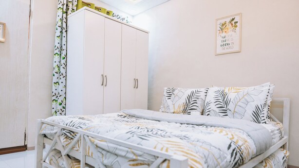 Un dormitorio con cama, armario y una pared con una cita inspiradora.