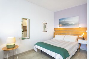 Ein Hotelzimmer mit Bett, Nachttisch, Lampe und einem Bild an der Wand.