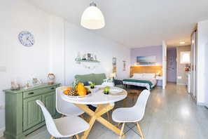 Ein moderner, gut beleuchteter Raum mit einem Essplatz für zwei Personen, einem grünen Schrank und einem Bett mit Blick.