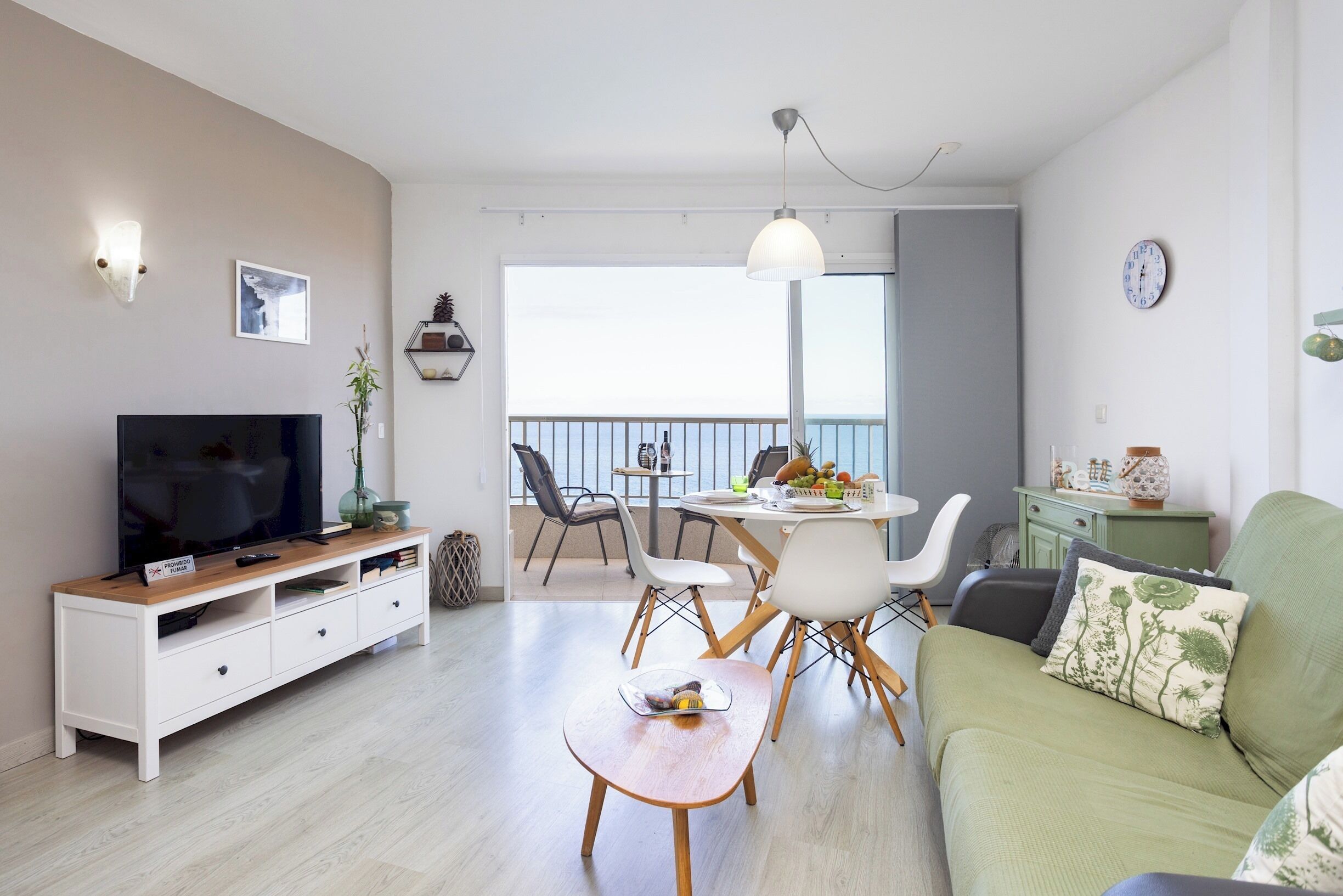 Un salon moderne avec un téléviseur à écran plat, une table à manger, des chaises et un canapé vert.