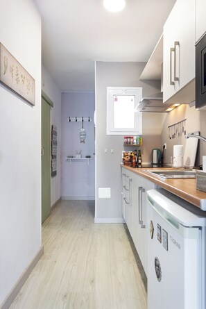 A modern kitchen with white cabinets, a wooden countertop, and a built-in dishwasher. - TenoHomes Atlantic View Icod Terrace (San Marcos)