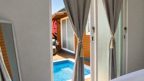 A room with a view of a swimming pool, curtains tied back, and a wooden deck area. - El Flamboyán Suite 3 with private plunge pool (Añasco)