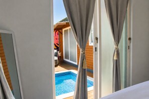 A room with a view of a swimming pool, curtains tied back, and a wooden deck area. - El Flamboyán Suite 3 with private plunge pool (Añasco)