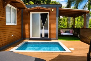 A pool area with a wooden deck, a sliding glass door leading to a bedroom, and a hanging chair in the background. - El Flamboyán Suite 3 | Private Plunge Pool (Añasco)