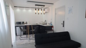A modern kitchen with a dining area, a black sofa, and a white door. - El Flamboyán Suite 3 with private plunge pool (Añasco)