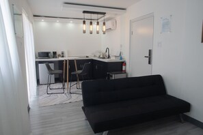 A modern kitchen with a dining area, a black sofa, and a white door. - El Flamboyán Suite 3 with private plunge pool (Añasco)