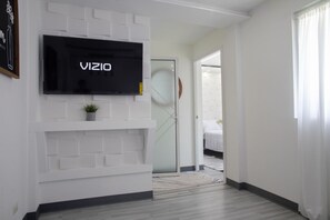 A modern interior with a mounted TV, a potted plant, and a white brick wall design. - El Flamboyán Suite 3 | Private Plunge Pool (Añasco)