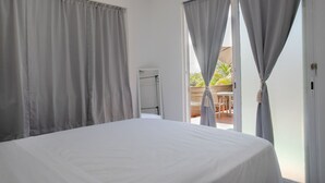 A bedroom with a bed, curtains, a door, and a view of an outdoor area. - El Flamboyán Suite 3 with private plunge pool (Añasco)