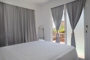 A bedroom with a bed, curtains, a door, and a view of an outdoor area. - El Flamboyán Suite 3 with private plunge pool (Añasco)