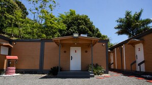 A building with a central entrance, numbered rooms, and a gravel driveway. - El Flamboyán Suite 3 with private plunge pool (Añasco)