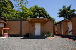 A building with a central entrance, numbered rooms, and a gravel driveway. - El Flamboyán Suite 3 with private plunge pool (Añasco)