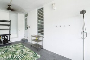 A clean, modern bathroom with a shower, a ceiling fan, and a small cart with items on it. - Jardines Casita | 5-Min Walk to Downtown Rincón (Ensenada)