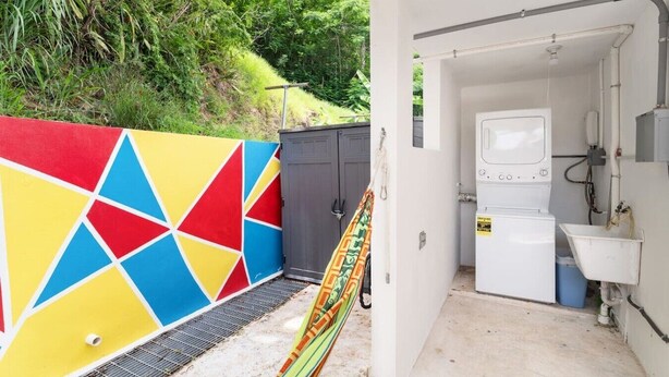 A laundry facility with a colorful wall, a washing machine, and a sink. - Jardines Casita - 5 min walk to downtown Rincon (Ensenada)