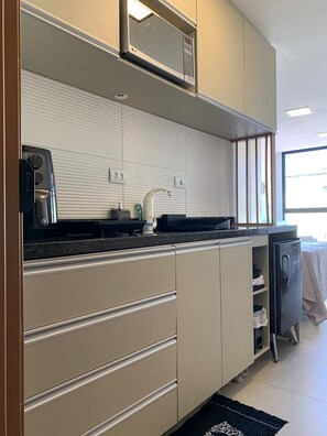 A modern kitchen with a microwave, stove, and refrigerator. - Apartment in Porto de Galinhas close to the main resorts. 5 minutes from the center. (Ipojuca)