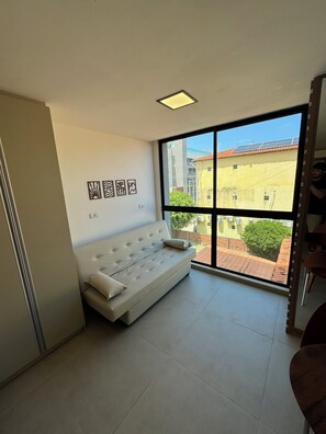 A room with a white sofa, a large window, and artwork on the wall. - Apartment in Porto de Galinhas close to the main resorts. 5 minutes from the center. (Ipojuca)