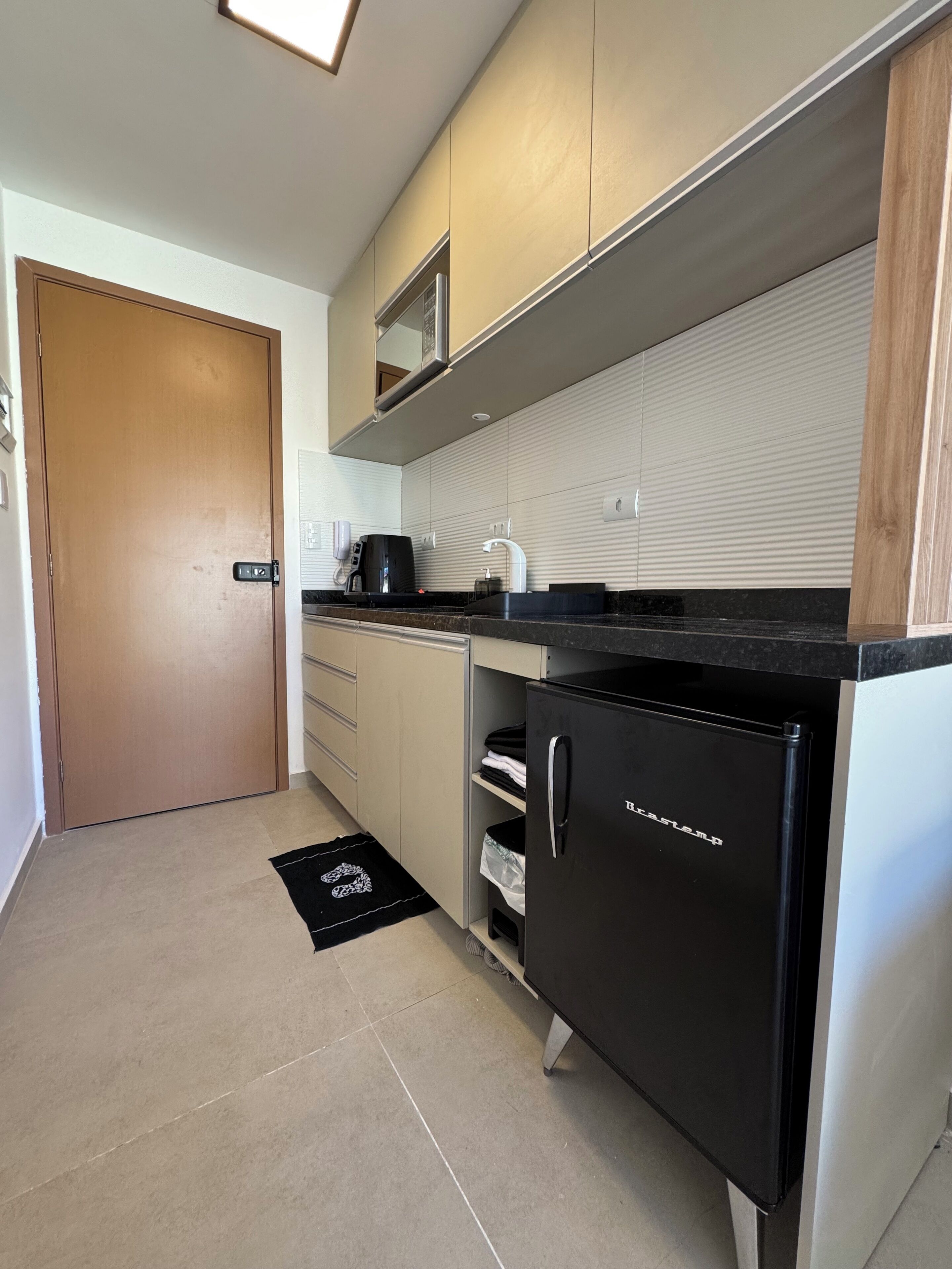 A modern kitchen with a black refrigerator, a coffee maker, and a microwave.