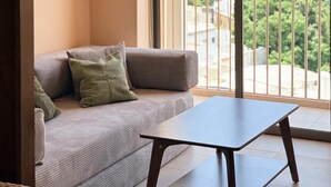 A balcony with a sofa and a table, an air conditioning unit, and a view of a cityscape. - The coolest spot to experience the city. (Mazatlán)