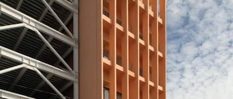 Un edificio de varios pisos con un llamativo letrero 'Macer', que presenta un diseño arquitectónico moderno con balcones y techo plano.