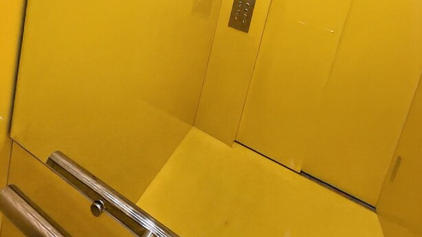 An elevator interior with a metallic control panel and reflective yellow walls. - The coolest spot to experience the city. (Mazatlán)