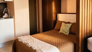 A bedroom with a bed, wooden wardrobe, and a bedside table. - The coolest spot to experience the city. (Mazatlán)
