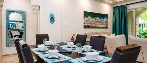 Comedor con una mesa dispuesta para cuatro personas, sillas y un cuadro en la pared.