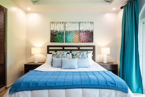 A hotel room with a bed, two bedside tables, a headboard, and a large painting above the bed.