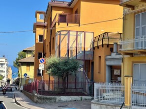 A yellow building with a glass facade, a red metal fence, and a white fence in front. - Casa Marietta - Studio Apartment, Sleeps 2 (Arenzano)