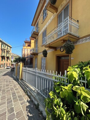 A yellow building with a white fence, a door, and a balcony with a metal railing. - Casa Marietta - Studio Apartment, Sleeps 2 (Arenzano)
