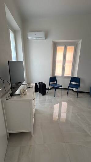 A room with a desk, two chairs, a television, and a window with blinds. - Casa Marietta - Studio Apartment, Sleeps 2 (Arenzano)