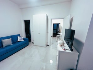 A modern living room with a blue sofa, a TV, and a white wardrobe. - Casa Marietta - Studio Apartment, Sleeps 2 (Arenzano)