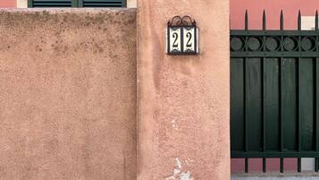 A building facade with a number plaque, a window with shutters, and a metal gate.