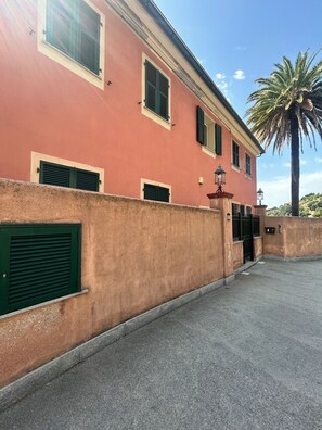 Ein Gebäude mit roter Fassade, grünen Fensterläden und einer Palme im Hintergrund.