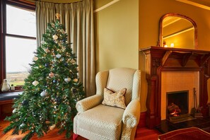 Une pièce chaleureuse avec un sapin de Noël, une cheminée et un fauteuil confortable.