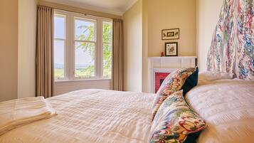 A bedroom with a large bed, a fireplace, and a view of the outdoors through the window.