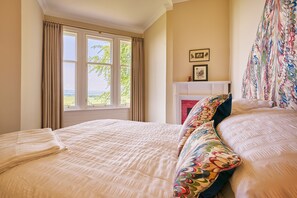 Une chambre avec un grand lit, une cheminée et une vue sur l’extérieur par la fenêtre.