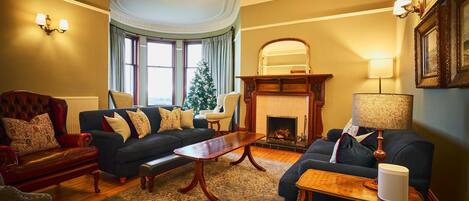 Un salon traditionnel avec une cheminée, deux canapés, une table basse et un sapin de Noël.