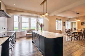 A modern kitchen with a large island, built-in appliances, and a view of the countryside. - Kinclune House Annex Luxury Mansion Angus Glens (Kirriemuir)