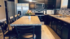 A kitchen with a granite countertop, stainless steel appliances, and dark cabinetry. - Spacious 5-bedroom building in serene Avon with AC (Avon)