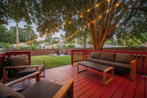 A deck with a red railing, a sofa, and two chairs.