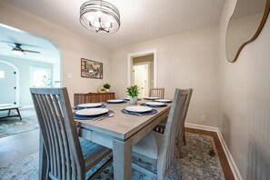 A dining room with a rectangular table, six chairs, and a chandelier.