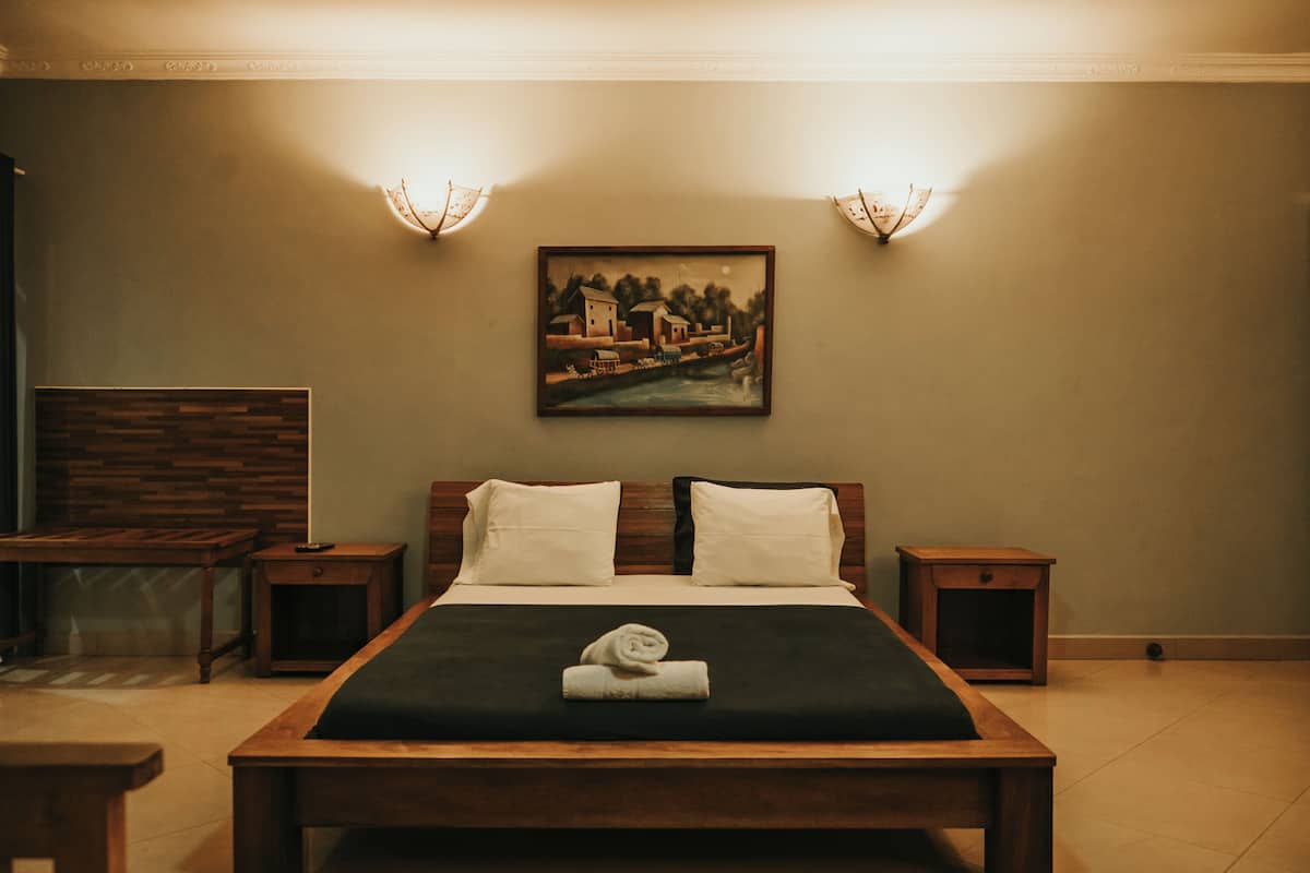 Un lit bien fait, avec une serviette pliée, deux tables de chevet, une commode et un tableau accroché au mur.